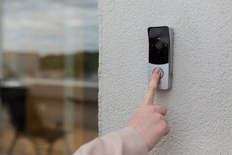 a hand pressing a video doorbell