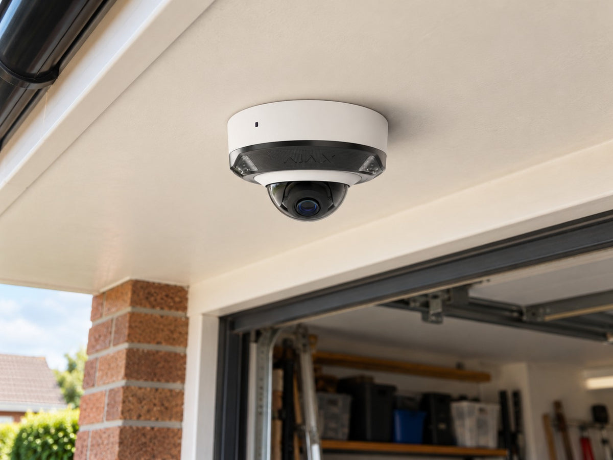 Ajax DomeCam Mini HL • 5MP 4mm • White installed in British home garage entrance beneath a flat cream soffit.