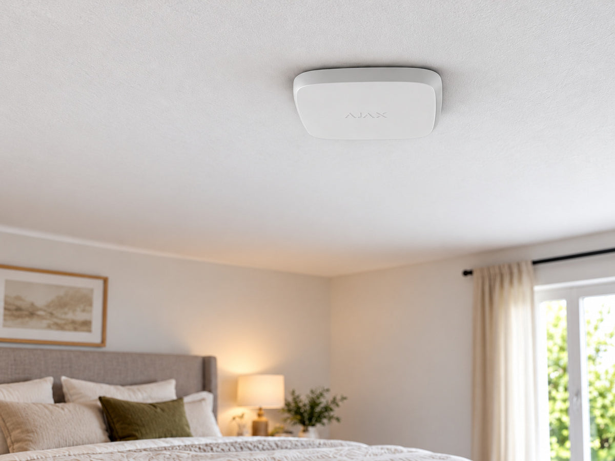 White Ajax FireProtect 2 SB Smoke/Heat alarm mounted flat against a bedroom ceiling.