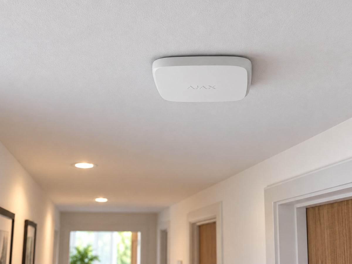 White Ajax FireProtect 2 SB Smoke/Heat alarm mounted flat against a hallway ceiling.