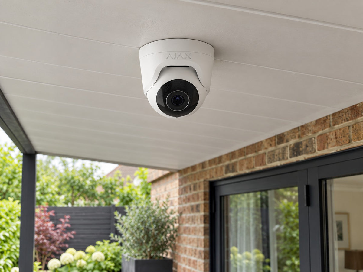 Ajax TurretCam • 5MP 4mm • White installed in British home covered rear patio, brick facade and planting below.