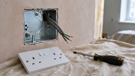 Galvanised steel electrical back box set into a plastered wall with twin-and-earth cable