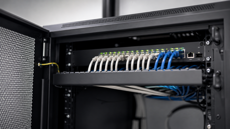 Rack-mounted network switch in a comms cabinet with ethernet cables patched in
