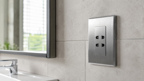 Brushed chrome shaver socket on a tiled bathroom wall beside a mirror and basin