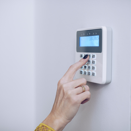 A women's hand using a burglar alarm control panel