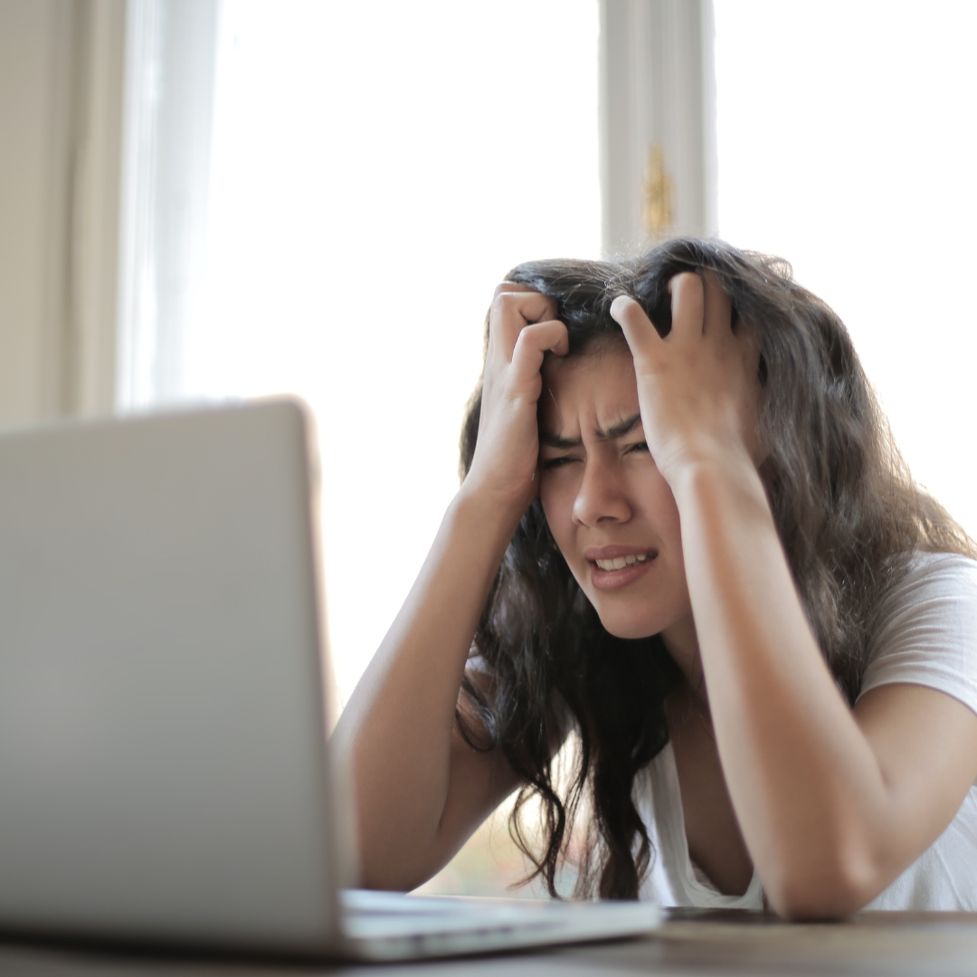 A woman using a laptop looking frustrated 