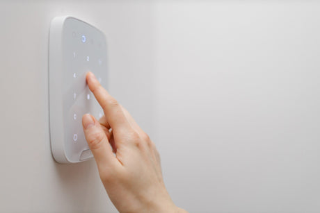 white smart switch on wall with hand pressing button