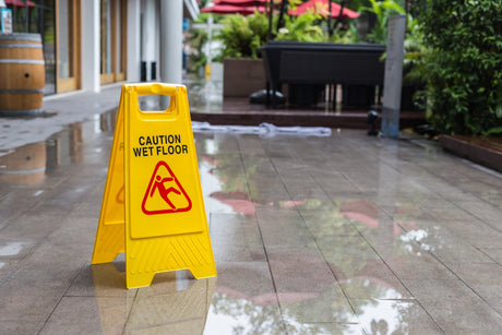 Yellow wet floor warning sign on the floor in hotel corridor