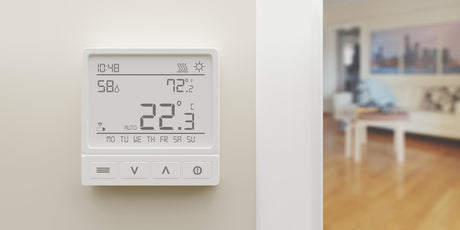 Digital thermostat on white wall Home heat temperature control device close up 