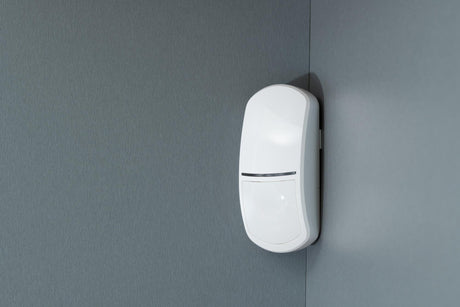 Combined radar and passive infrared sensor on a grey wall