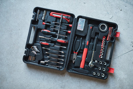 Open tool box with red hammer and screwdriver on concrete floor