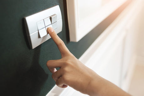 a hand pressing a switch on a modern home interior wall 