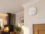 Aico Ei208WRF shown at a room with a wood-burning stove.