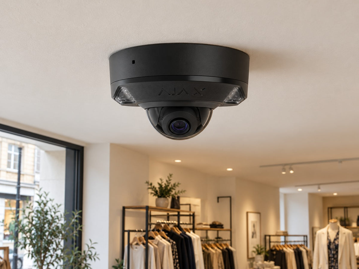 Ajax DomeCam Mini HL • 5MP 2.8mm • Black installed in British boutique clothing shop interior, warm off-white ceiling.