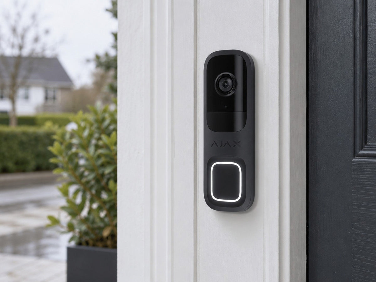 Ajax DoorBell Graphite shown at a white entrance frame.