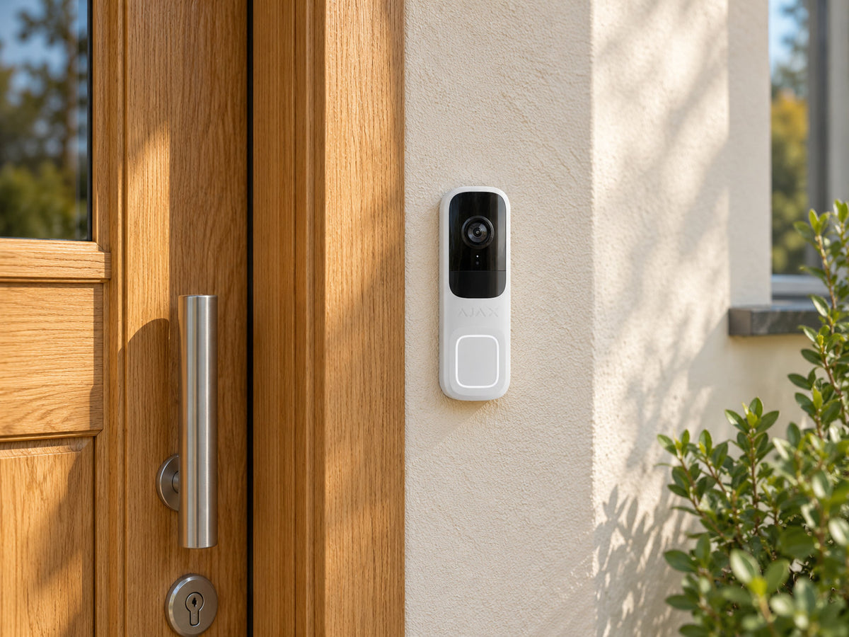 Ajax DoorBell white mounted on a rendered wall beside an oak front door.
