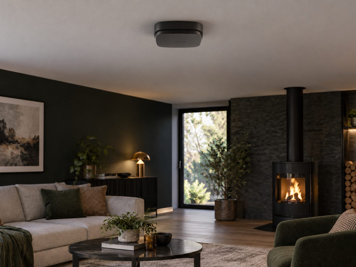 Ajax FireProtect 2 AC CO in a dark-accent modern living room with a distant wood stove.