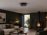 Ajax FireProtect 2 AC CO in a dark-accent modern living room with a distant wood stove.