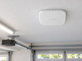 White Ajax FireProtect 2 AC Heat/CO alarm mounted flat against a garage ceiling.