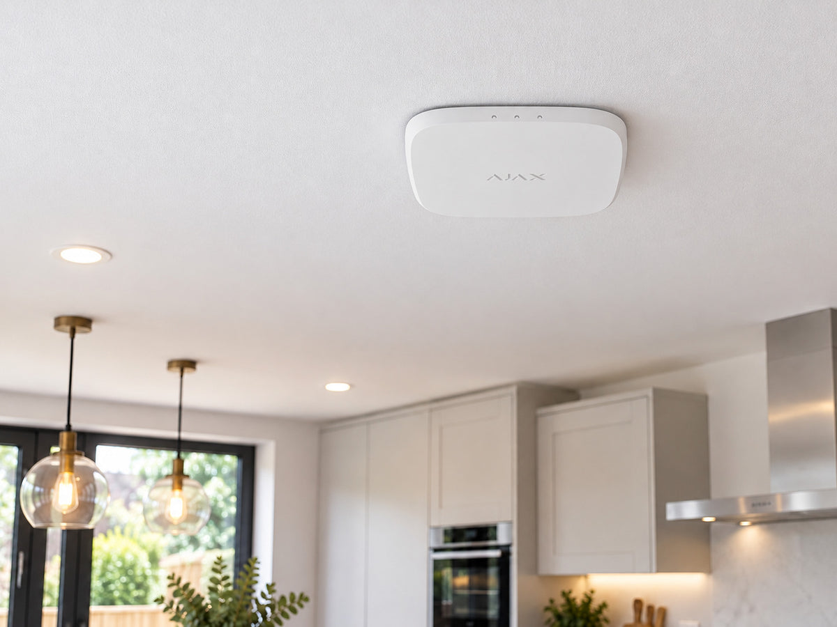 White Ajax FireProtect 2 AC Heat/CO alarm mounted flat against a white kitchen ceiling.