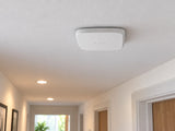 White Ajax FireProtect 2 SB Smoke/Heat alarm mounted flat against a hallway ceiling.