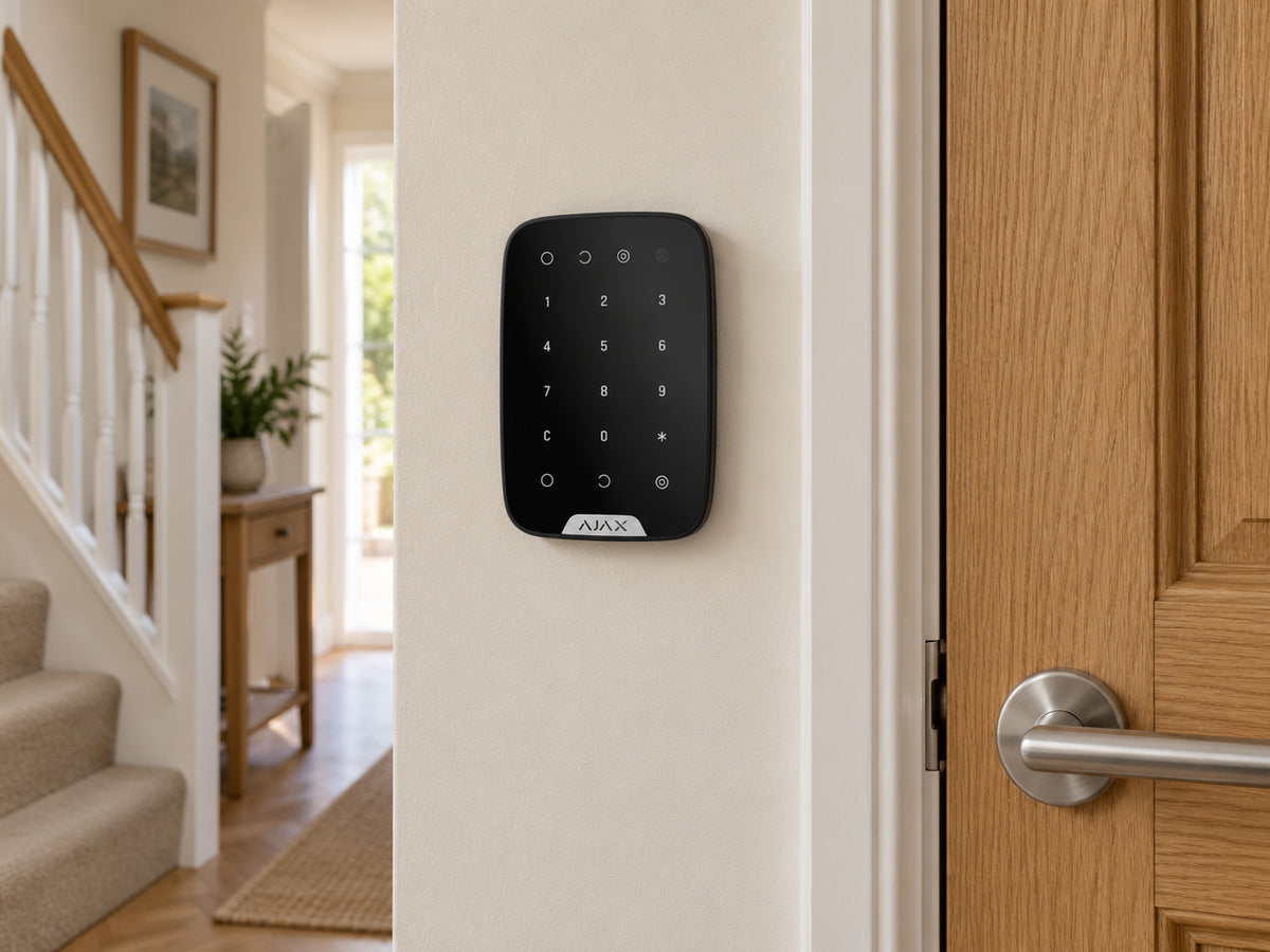 Ajax KeyPad black mounted on a hallway wall beside a timber door.