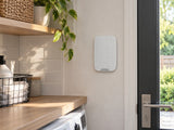 Ajax KeyPad Fibra White shown at a reception-area wall.