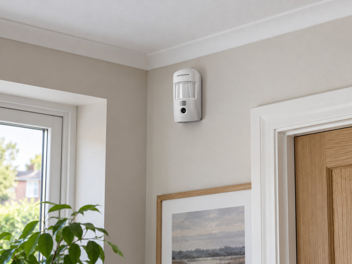 Ajax MotionCam Fibra white mounted upright high on a living-room wall.