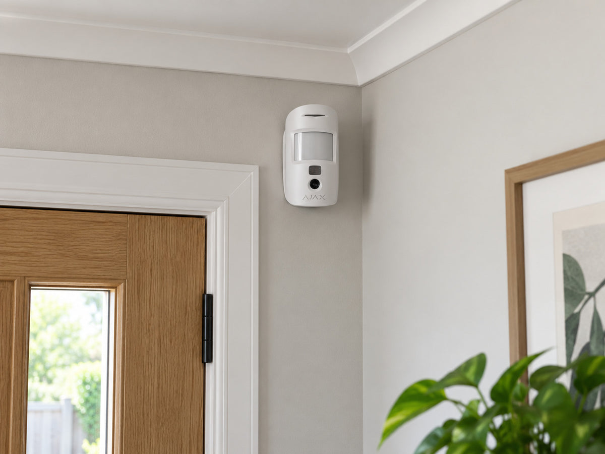 Ajax MotionCam Fibra white mounted upright above a home-office entrance.