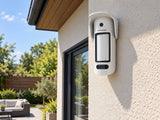 Ajax MotionCam Outdoor HighMount PhOD shown at a house wall beneath eaves.