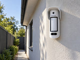 Ajax MotionCam Outdoor HighMount PhOD shown at a wall beneath eaves.