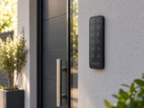 Ajax Superior KeyPad Outdoor Fibra Graphite mounted on a rendered wall beside an entrance.