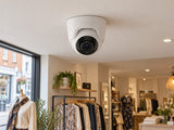 Ajax TurretCam • 5MP 4mm • White installed in British boutique clothing shop interior, warm off-white ceiling.