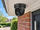 Hikvision DS-2CD2346G3-IZ2UY • Black installed in A UK home entrance beneath a white horizontal canopy, red brick wall and planted driveway below.