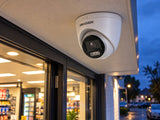 Hikvision DS-2CE72KF3T-LE (3.6 mm) shown at an evening shop entrance.