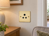 Knightsbridge FP5APB polished brass lighting socket installed in a dry UK living-room wall near an unconnected reading lamp.