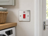 Knightsbridge FP8331NPC polished chrome double-pole switch installed in a dry UK utility-room wall beside a cupboard.