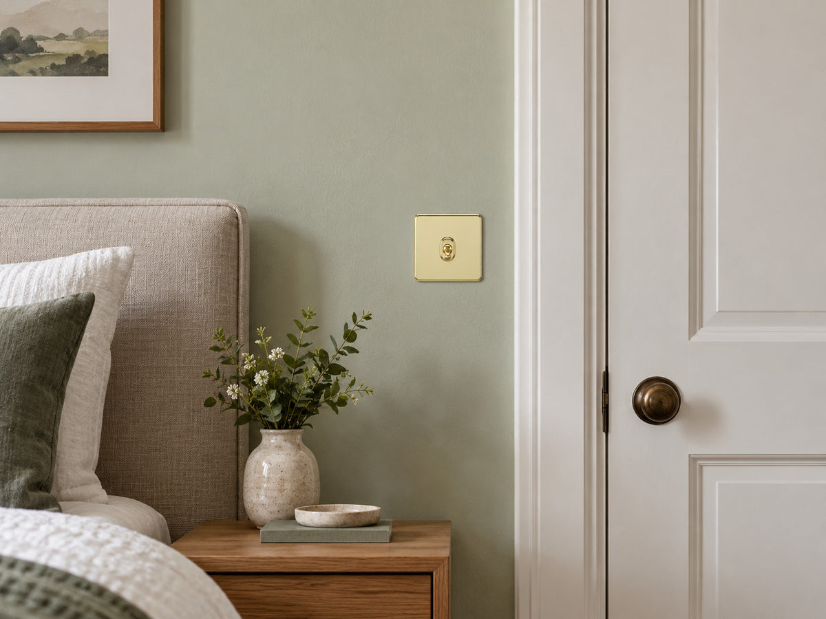Knightsbridge SF1TOGPB polished brass toggle switch fitted flush in UK bedroom beside a doorway.
