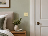 Knightsbridge SF1TOGPB polished brass toggle switch fitted flush in UK bedroom beside a doorway.
