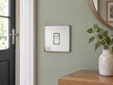Knightsbridge SF2000PC polished chrome light switch installed on a UK living-room entrance wall with muted sage paint.