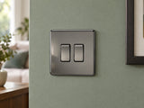 Knightsbridge SF3000BN black nickel light switch fitted on a UK living-room entrance wall with muted sage paint.