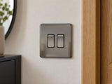 Knightsbridge SF3000BN black nickel light switch fitted on a UK hallway wall beside an oak door frame.