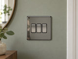 Knightsbridge SF4000BN black nickel light switch fitted on a UK living-room entrance wall with muted sage paint.