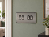 Knightsbridge SF4100BN black nickel light switch fitted on a UK living-room entrance wall with muted sage paint.