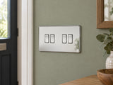 Knightsbridge SF4100PC polished chrome light switch installed on a UK living-room entrance wall with muted sage paint.