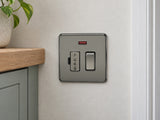Knightsbridge SF6300NBN black nickel fused spur fitted on a dry UK utility-room wall near a cupboard.